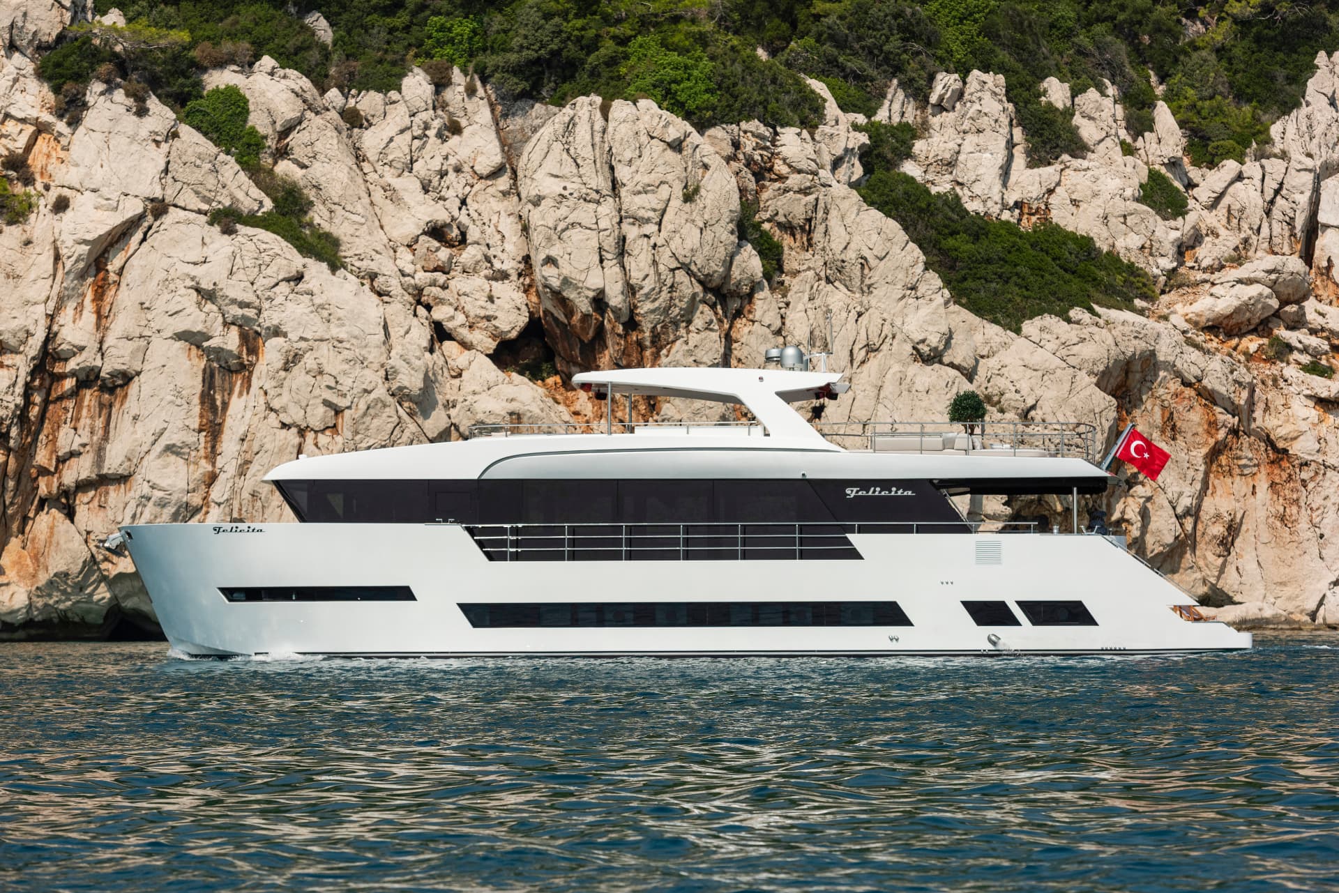 Full profile: 26.90 metres of aluminium against a rocky cove